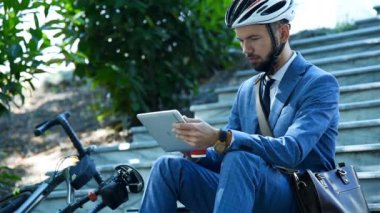 Sakallı İşadamı merdivenlerde oturuyor ve dijital tablet bilgisayar kullanıyor. İş ve Şehir Biçimi Konsepti