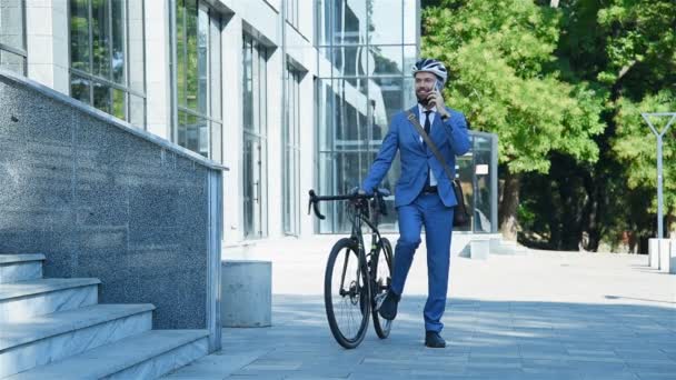 オフィスビルで携帯電話で話す自転車と若いひげを生やしたビジネスマン背景 — ストック動画