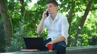 Parkta oturan ve cep telefonuyla konuşan tüccar. Ticaret ve Çalışma Konsepti.