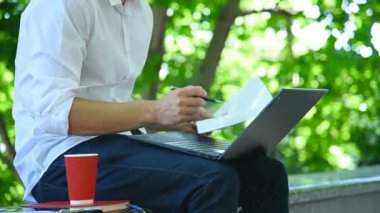 Tüccar parkta oturuyor ve iş raporlarını inceliyor. Ticaret ve İletişim Konsepti. Kapat.