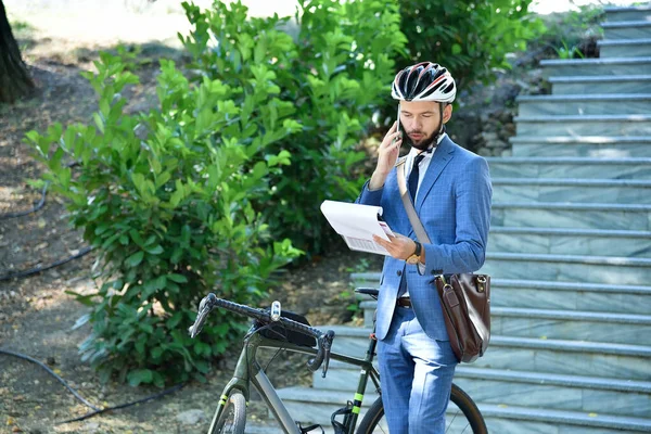 Businessman analyzes report and talking on phone with bicycle. Business and urban style concept