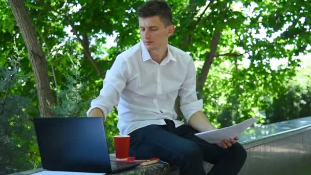 Młody Biznesmen Siedzi Parku Analizuje Raport Biznesowy Laptopie Koncepcja Handlu — Wideo stockowe