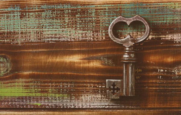 Ancient key. Retro background. Wooden surface painted. The texture of wood, strokes of colored paints. Empty space. Aged creative wooden background