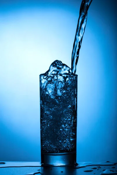 Fluxo Água Derrama Vidro Close Spray Água Fundo Azul — Fotografia de Stock