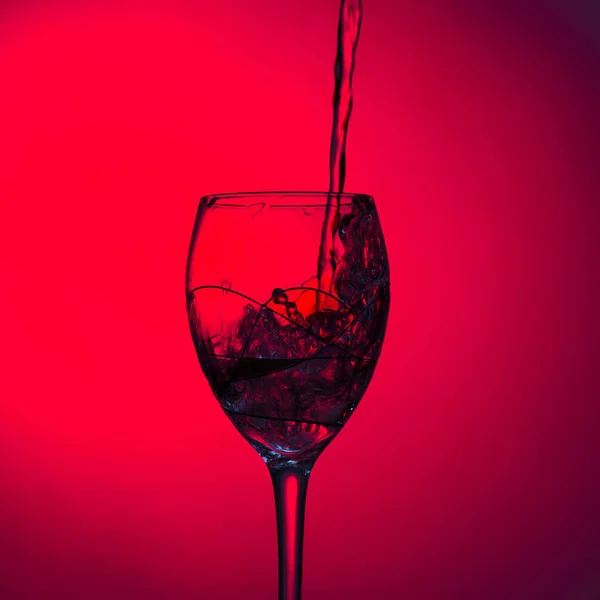 Flüssigkeit Ein Weinglas Auf Rotem Hintergrund Gegossen Nahaufnahme — Stockfoto