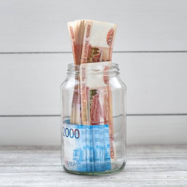 Cam kavanoz hafif bir arka plan üzerinde para ile dolu. Rus banknotları
