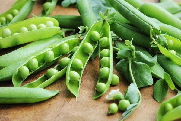 Mogna baljor av gröna ärtor, färska gröna ärtor på träbord, närbild — Stockfoto