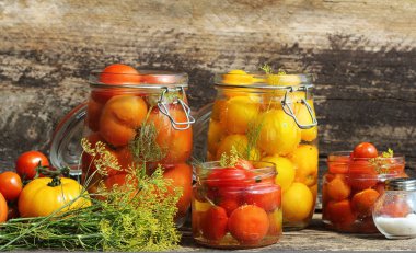 Turşusu domates kavanoz ahşap masa üzerinde. Çeşitli - kırmızı sarı, turuncu renkler domates fermente işlem cam kavanozlar