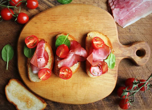 Bruschetta Prosciutto Ham Cherry Tomatoes Green Spinach Cutting Board Top — Stock Photo, Image