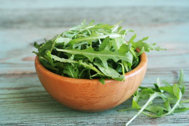 Taze roka yaprakları ahşap kase, rucola ahşap eski arka plan üzerinde .