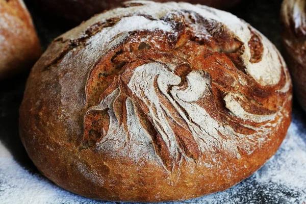Čerstvě upečený bochník domácího chleba na rustikální tmavé pozadí — Stock fotografie