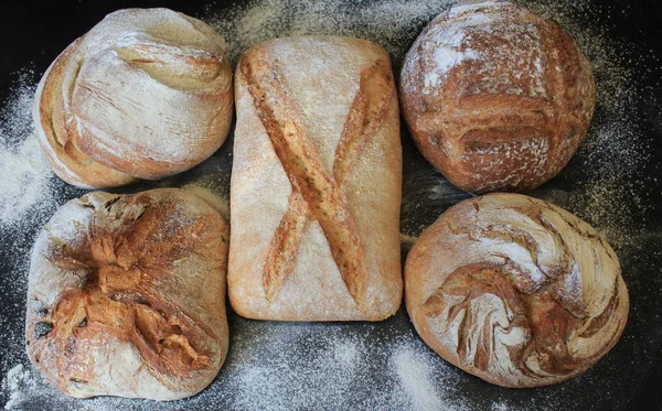 Auswahl an frischem Brot auf schwarzem Hintergrund. Konzept des Kochens, erfolgreicher Unternehmer oder Start-up. — Stockfoto