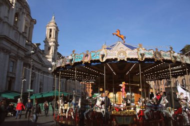 Roma, İtalya-28 Aralık 2018: Turistler Piazza Navona'yı antik atlıkarıncayla, Noel pazarında Santagnese kilisesinin arka planda olduğu Roma, İtalya'da dolduruyor.