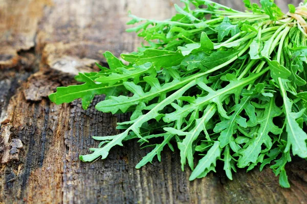 Hojas de rúcula verde fresco sobre fondo rústico de madera. Ensalada de rúcula, comida saludable, dieta. Concepto nutricional — Foto de Stock