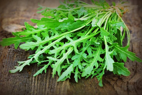 Folhas de arugula verdes frescas no fundo rústico de madeira. Salada de foguete ou rucola, comida saudável, dieta. Conceito de nutrição — Fotografia de Stock