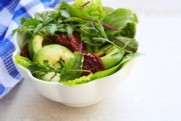 Insalata di avocado fresco con pomodori secchi, lattuga, foglie di barbabietola rucola sullo sfondo bianco. Concetto di cibo sano. Cibo vegano . — Foto Stock