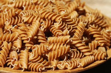 Fusilli 'yi tabağa koy. Ahşap bir masanın üzerinde entegral makarna