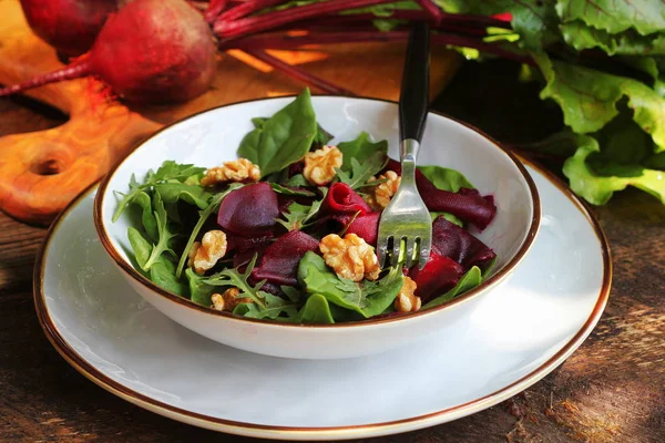 Čerstvý řepkový salát s čerstvým sladkým špenátem, arugula, ořechy na dřevěném pozadí — Stock fotografie