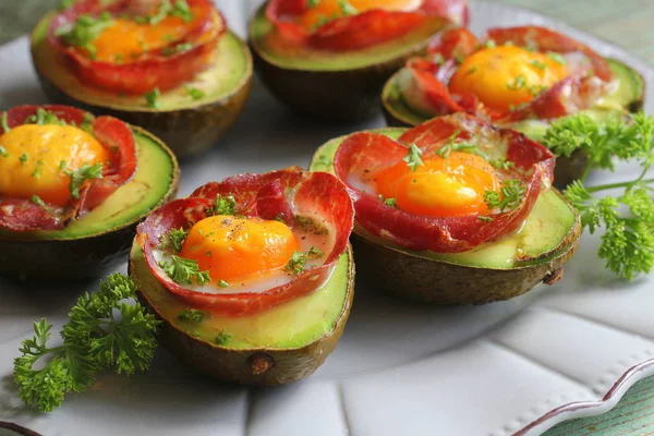 Avocado Egg Boats with bacon on dark wooden background. Top view — Stock Photo, Image