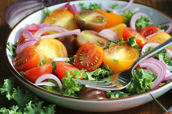 Salada verde fresca com tomates cereja, couve de repolho, cebolas na tábua de redução. Fundo de madeira — Fotografia de Stock
