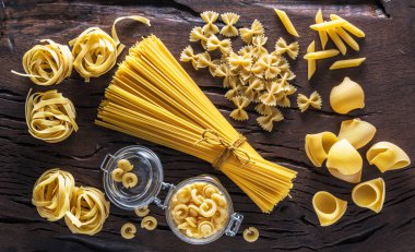 Different pasta types on the wooden table. clipart