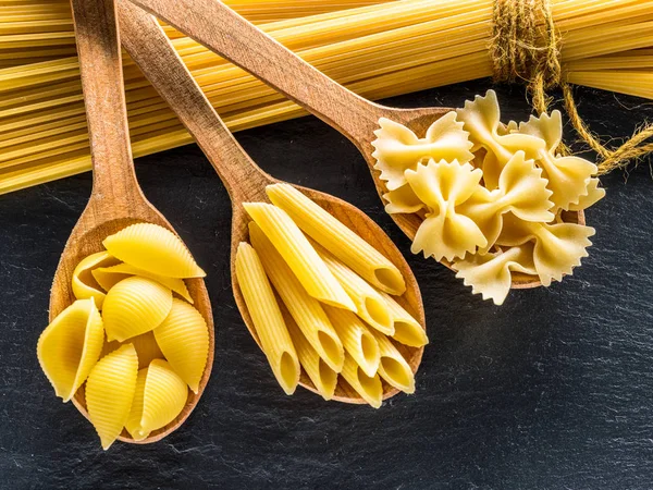 Different Pasta Types Wooden Spoons Table Top View — Stock Photo, Image