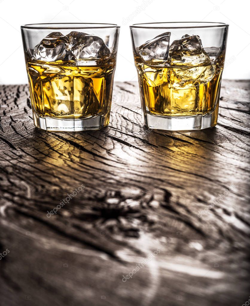 Whiskey glasses or glasses of whiskey with ice cubes on the table at white background.