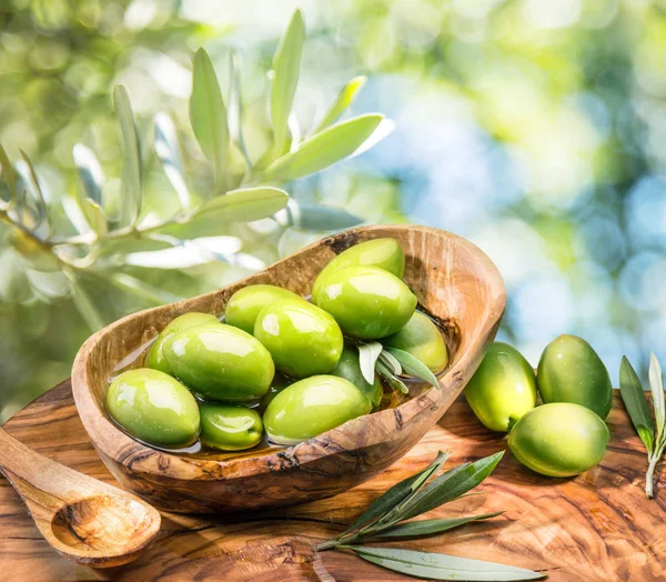 Bütün tablo zeytin masada ahşap kase. Doğa arka plan.