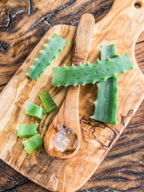 Fresh aloe leaves and aloe gel in the wooden spoon on the table. clipart