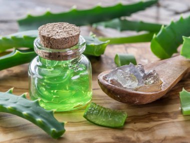 Ahşap masadaki kozmetik kavanozunda taze aloe yaprakları ve aloe jeli..