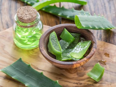 Ahşap masadaki kozmetik kavanozunda taze aloe yaprakları ve aloe jeli..