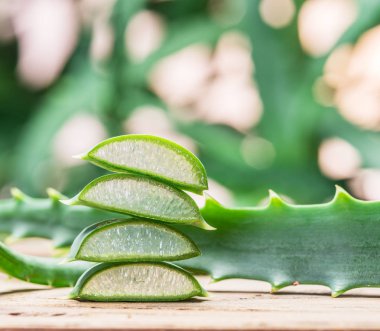 Ahşap masadaki kozmetik kavanozunda taze aloe yaprakları ve aloe jeli..