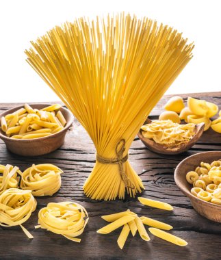 Different pasta types on wooden table. White background. clipart