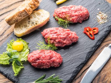 Steak tartare kapari, salatalık turşusu ve doğranmış soğan ile servis.