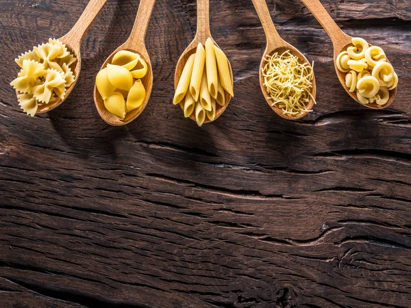 Masadaki tahta kaşıklarda farklı makarna tipleri. Üst görünüm.