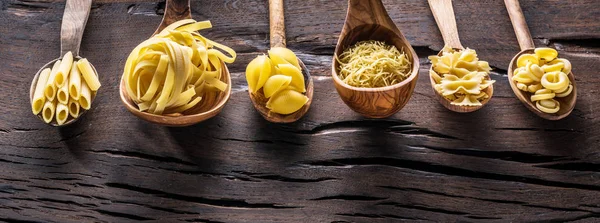 Masadaki tahta kaşıklarda farklı makarna tipleri. Üst görünüm.