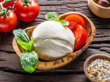 Buffalo mozzarella ahşap kase ve kiraz domates masada.