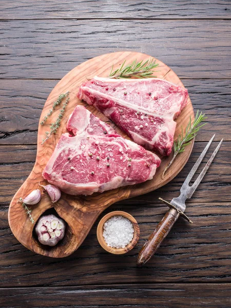 Ahşap kesme tahtası üzerinde baharatlar ile T-bone biftek.