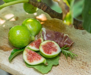 Olgun incir meyve ve pastırma veya prosciutto. Yiyecek içecekler eşlik edecek.