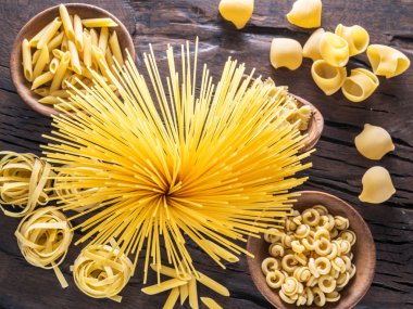 Different pasta types on the wooden table. Top view. clipart