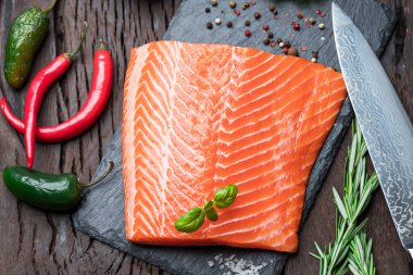 Otlar ve baharatlar ile siyah kesme tahtası üzerinde taze somon fileto. Üstten Görünüm.