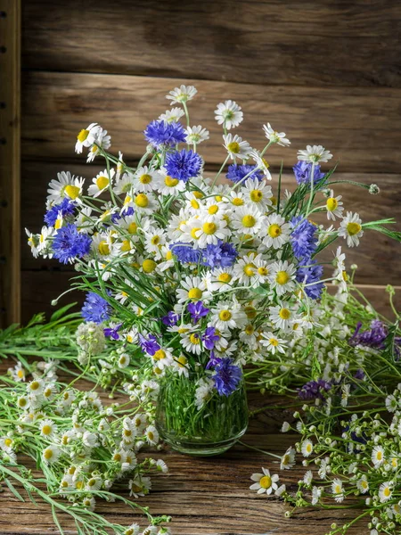 Chamomiles ve Peygamber ahşap masa üzerinde vazoda oluşan.