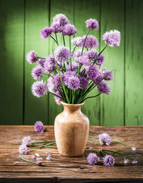 Tahta masadaki vazoda bir buket soğan (soğan soğanı) çiçeği.