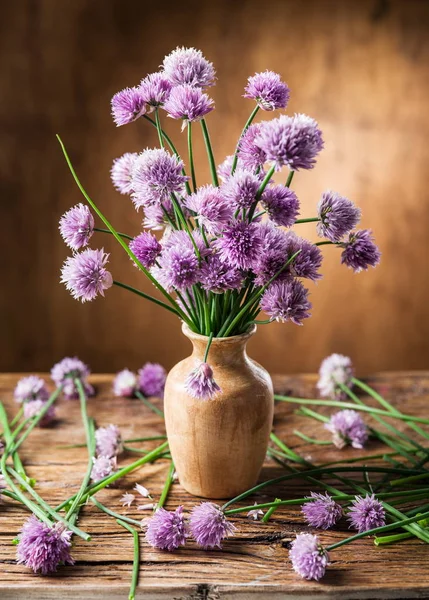 Tahta masadaki vazoda bir buket soğan (soğan soğanı) çiçeği.