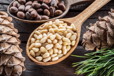 Çam fıstığı ahşap masa üzerinde kaşık ve çam fıstığı koni. Organik gıda.