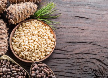 Çam fıstığı ahşap masa üzerinde kaşık ve çam fıstığı koni. Organik gıda.