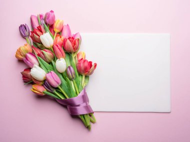 Lale ve pembe bir arka plan üzerinde beyaz kağıt renkli buket.