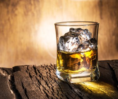 Whiskey glass or glass of whiskey with ice cubes on the wooden background. clipart