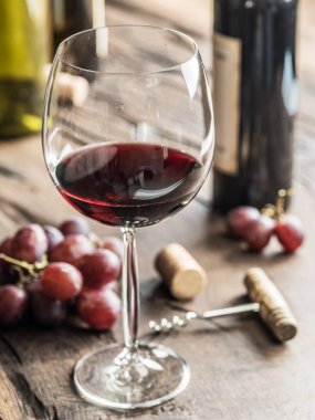Bir bardak kırmızı şarap masanın üzerinde. Şarap şişesi ve arka plan, üzüm.