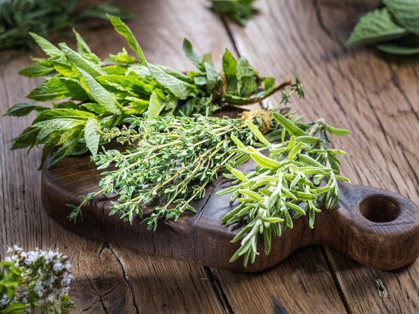 Different bunches of fresh herbs on the wooden table.